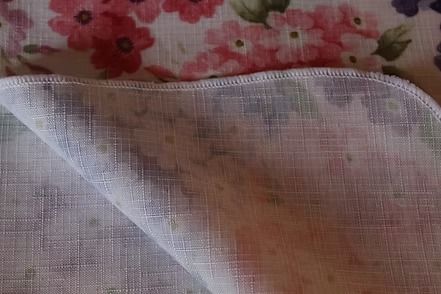 Floral fabric pattern with red, pink, purple, and white blossoms on a beige background