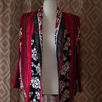 Red and black floral kimono-style jacket on a mannequin against patterned wallpaper