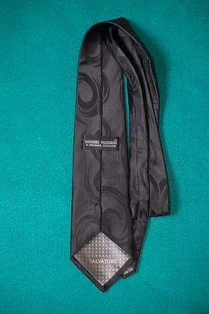 Black patterned necktie on a teal background