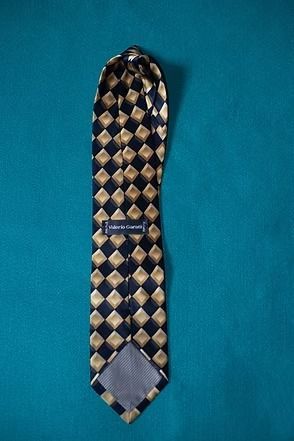 Blue and beige diamond-patterned necktie on a teal background