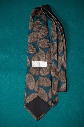 Blue patterned necktie with tan leaf design on a teal background