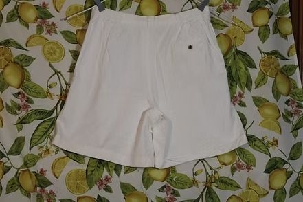 White shorts laid flat on a leafy patterned background.