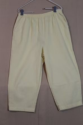 Light cream pants hanging on a gray hanger against a plain background