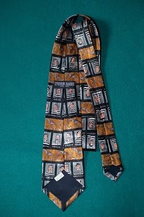 Black necktie with orange and white patterned panels on a teal background