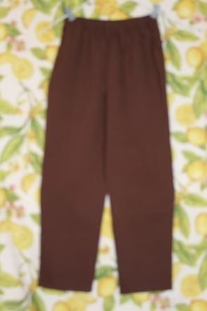 Brown pants laid flat on a yellow-and-green floral background.