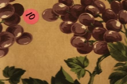 Patterned wallpaper with green leaves and clusters of purple flowers on a beige background