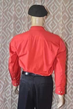 Mannequin wearing a red button-up shirt, black beret, and dark trousers against a patterned backdrop