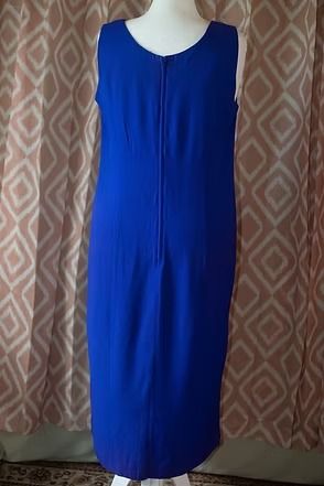 Blue sleeveless dress on a mannequin against a patterned curtain.