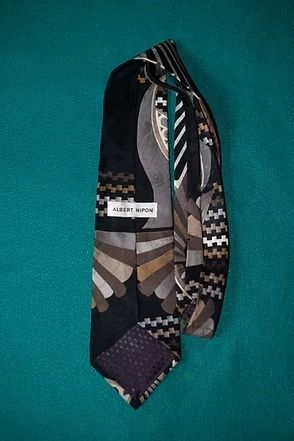 Patterned black and white necktie on a teal background