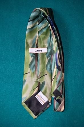Colorful patterned necktie hanging against a teal wall