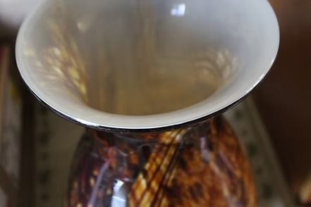Decorative glass vase with brown and gold swirls on a red textured cloth