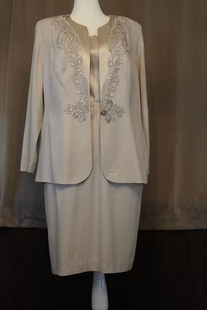 Cream-colored embroidered jacket and skirt displayed on a mannequin.