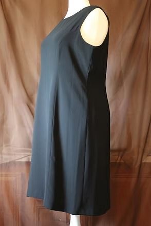 Black sleeveless dress hanging against a tan backdrop