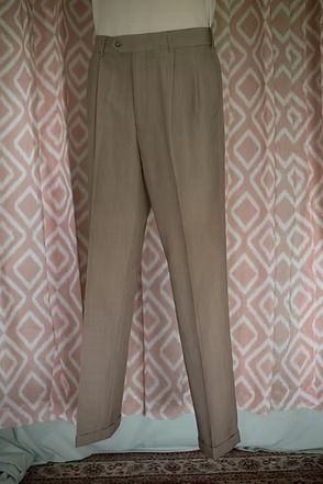 Beige trousers hanging against a patterned curtain backdrop.