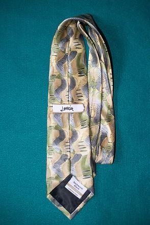 Patterned necktie with blue, green, and beige zigzag design on a teal background