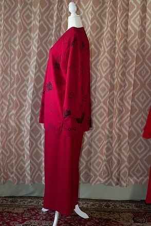 Red two-piece outfit on a mannequin against patterned curtains.