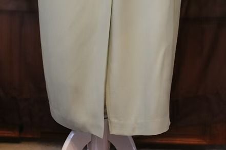 Light gray formal jacket and skirt outfit on a mannequin against a dark backdrop.