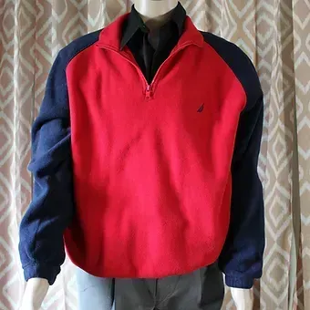 Red and navy quarter-zip pullover over a black shirt against a patterned curtain background