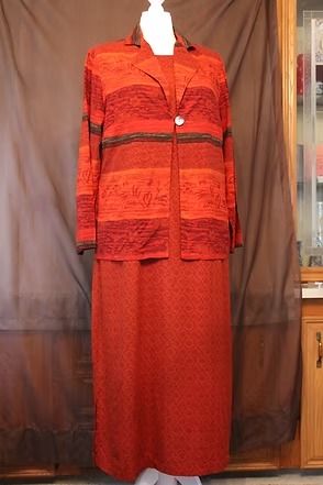 Red long dress on a mannequin against a brown curtain backdrop.