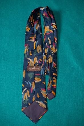 Patterned navy necktie with colorful leaf design on a teal background