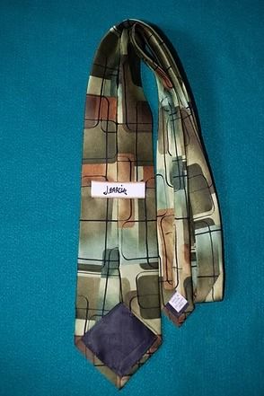 Abstract patterned necktie with brown, tan, blue, and red geometric blocks on a teal background