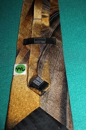 Close-up of a patterned gold and black necktie on a teal background