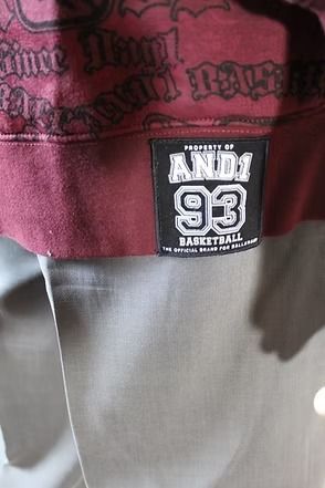 Mannequin wearing a black beret, dark shirt, and burgundy jacket against a patterned curtain.