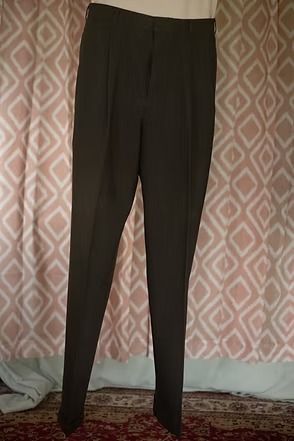 Black slim-fit pants hanging against a patterned curtain backdrop.