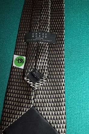 Black patterned necktie with a textured fabric, laid on a teal background