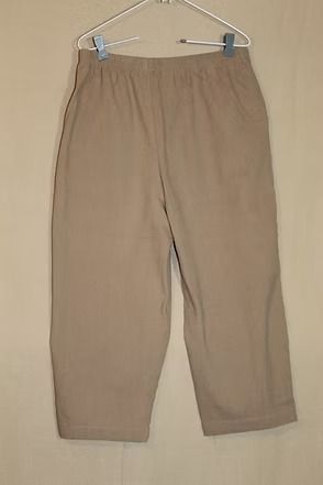 Beige pants hanging on a hanger against a plain background
