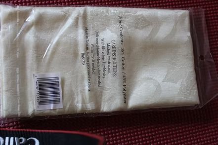 Close-up of white patterned fabric with black text and a pink “93” sticker on the right edge