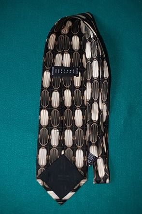 Black necktie with white geometric pattern on a teal background