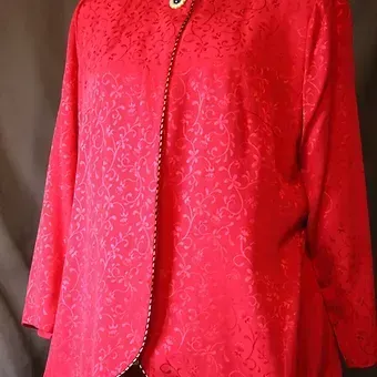 Red textured embroidered jacket with black piping and button closure on a mannequin torso