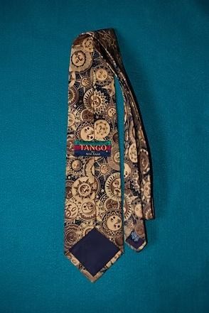 Patterned tie with gold and brown circular designs on a blue background