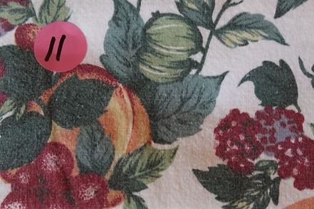 Floral and fruit-patterned fabric with roses, grapes, and leaves on a cream background