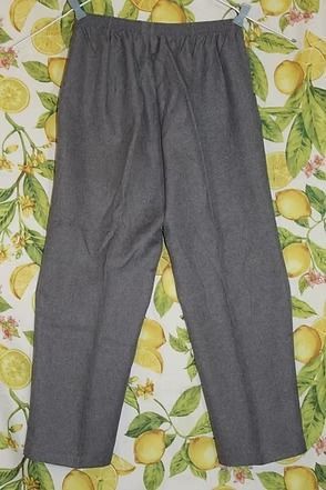 Gray pants laid flat on a lemon-patterned fabric background.