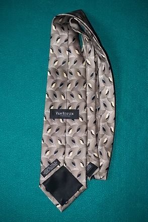 Silver patterned necktie on a teal background