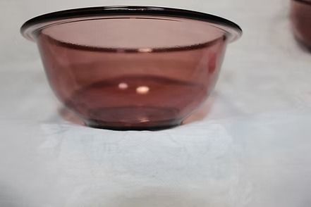 Top-down view of a pink glass bowl on a white surface with a small pink note nearby.