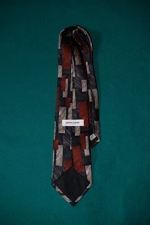 Patterned necktie in red, gray, white, and black on a teal background