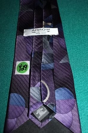 Purple patterned necktie on a green surface