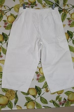 White pants laid flat on a patterned leaf-print surface.