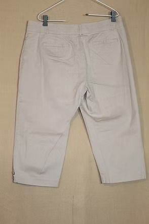 Light gray pants hanging on a hanger against a beige background