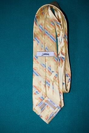 Patterned beige necktie with blue and red diagonal stripes on a teal background