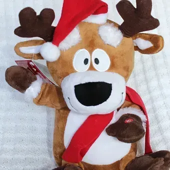 Plush reindeer toy wearing a red Santa hat and scarf, waving with a cheerful expression
