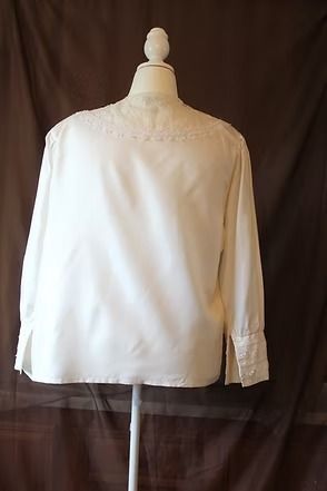 White lace-collared blouse with a small yellow flower clasp at the neckline