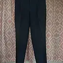 Dark pants hanging against patterned wallpaper.