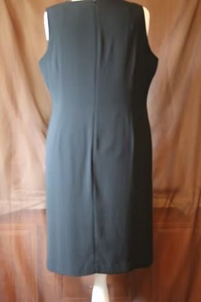 Black sleeveless dress hanging against a tan backdrop