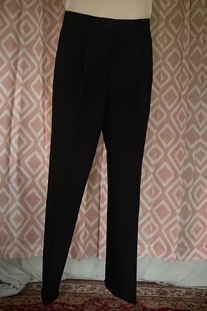 Black trousers hanging against a patterned wall.