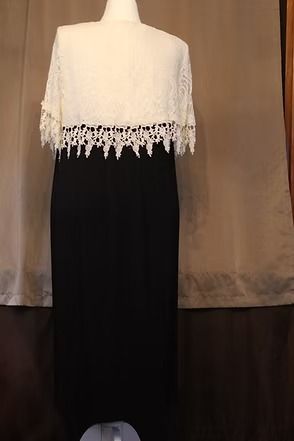 White lace top over long black skirt on a dress form against a brown curtain backdrop