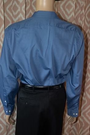 Mannequin wearing a blue button-up shirt, black pants, and a black beret against a patterned curtain background